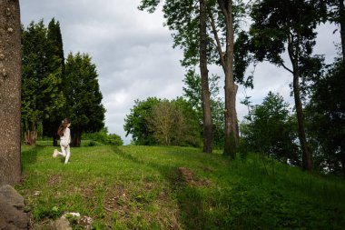 Çimenli bir alanda ağaçlar ve yeşilliklerle oynamayı seven bir çocuk..