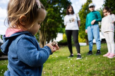 Canlı bir park ortamında aile tarafından çevrelenmiş doğayı keşfeden bir çocuk.
