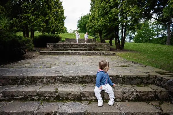 Dışarıda, yemyeşil bir ortamda oynayan çocukların sakin bir sahnesi..