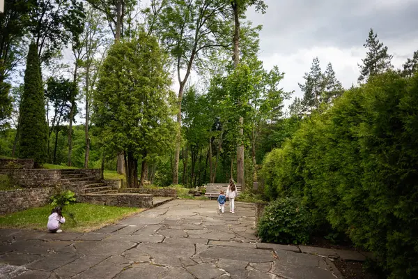 Huzurlu bahçe sahnesinde yemyeşil yollarda yaşayan insanlar var..