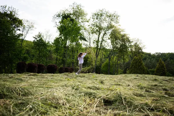Yeşilliklerle çevrili güneşli bir çimenlikte açık hava aktivitelerinden hoşlanan bir kız.