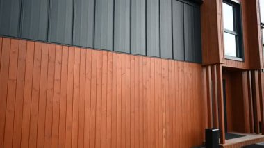 Modern bir ev, ahşap ve metal kaplama panelleri ile benzersiz bir tasarıma sahiptir..