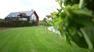 Geniş yeşil çimenli ve açık hava mekanlı modern bir ev manzarası..