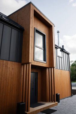 Dikey ahşap kaplama ve şık pencere yerleştirme tasarımlarıyla modern ev cephesi.