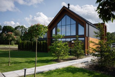 Geniş pencereli, bahçeli ve doğal çevresi olan çağdaş ahşap ev.