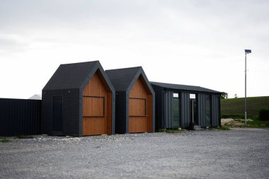 Two unique small wooden buildings designed with contrasting materials on a countryside property.