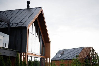 Modern ahşap bir evin mimari tasarımı. İçinde cam ve metalik bir çatı var.