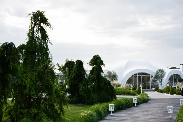 Canlı peyzaj ile çevrili beyaz kubbe şekilli modern bir bina.