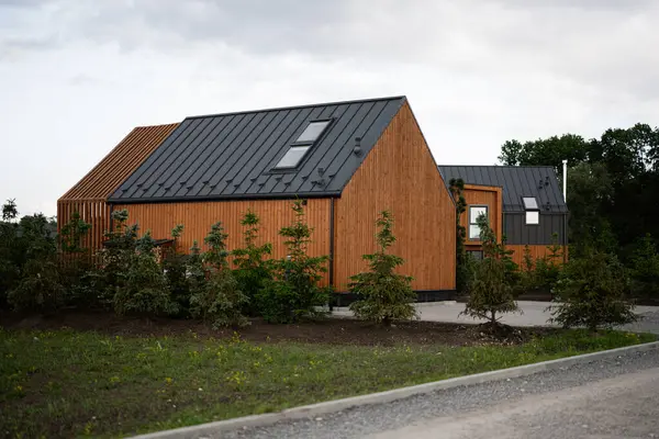 Modern mimarisi ve metalik çatıları olan ahşap evler, peyzaj ve doğa ile çevrili.