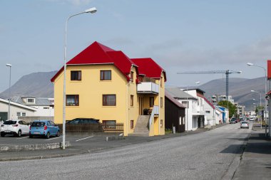 Akranes, İzlanda - 15 Haziran 2025: Açık gökyüzü altında Akranes 'te renkli evlerin yer aldığı canlı bir mahalle sahnesi.