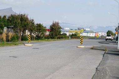 Akranes, İzlanda - 15 Haziran 2025: Akranes, İzlanda 'da sanayi binaları ve ağaçlarıyla huzurlu bir kent caddesi.