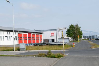 Akranes, İzlanda - 15 Haziran 2025: Akranes, İzlanda 'da Hsasmijan sanayi binaları ve bir yol tabelasıyla sokak manzarası