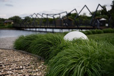 Dekoratif beyaz küre ve geometrik köprü serin park tasarımını geliştirir.