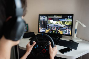 Kyiv, Ukrayna - 17 Haziran 2025: Çevirmeli oyun deneyimi için direksiyon kontrolü kullanan bir kişi