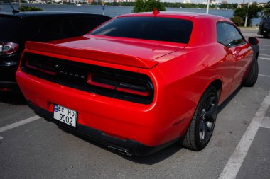 Ternopl, Ukrayna - 17 Haziran 2025: Canlı kırmızı Dodge Challenger arabası, lüks tasarımı şehir limanında park edilmiş.