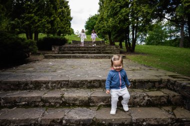 Aile bir park ortamından izlerken, çocuk taş basamakları keşfediyor
