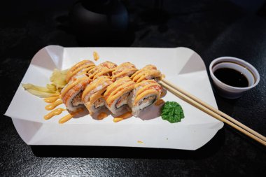 Modern bir kağıt tabakta sosla serpiştirilmiş güzel bir suşi rulosu.