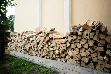 Dışarıdaki sarı duvarın yanına düzgünce istiflenmiş bir odun yığını..