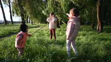 Neşeli kızlar eğleniyor ve doğada bir sopayla oynuyorlar..