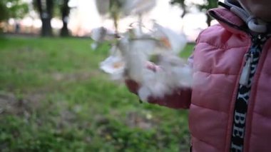Doğanın güzelliğinden büyülenmiş meraklı küçük kızlar, açık havada narin beyaz çiçekleri incelikle inceliyorlar..