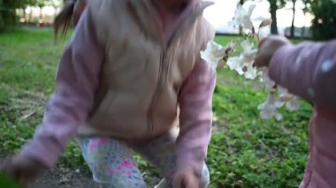 Genç kızlar dışarıda beyaz çiçeklerle oynayarak mutluluğu ve bağı paylaşıyorlar..