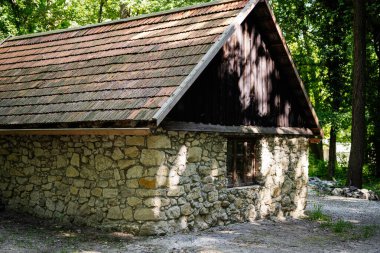 Güneşli bir günde yemyeşil bir ormanda yuva yapmış rahat taştan bir kulübe.