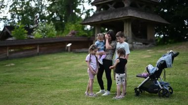 Bir anne ve çocukları birlikte güzel yeşil bir park ortamında keyifli anlar yaşarlar..