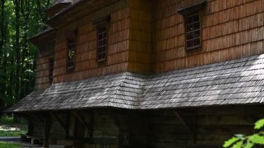 Huzurlu bir ormanda yemyeşil ağaçlarla çevrili karmaşık kiremit detaylarıyla antik ahşap kilise..