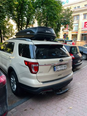Trnopil, Ukrayna - 24 Haziran 2025: Beyaz Ford Explorer SUV Çatısı olan bir depolama kutusu diğer arabaların yanında bir şehir caddesinde park