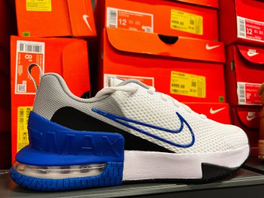 Kyiv, Ukrayna - 24 Haziran 2025: Turuncu ayakkabı kutularının arasında bir spor mağazasında sergilenen şık beyaz ve mavi Nike spor ayakkabısı