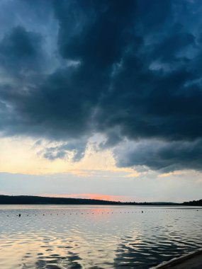 Huzurlu bulutlu gün batımı sahnesi. Huzurlu bir göl ve ışığı yansıtan sakin sular.