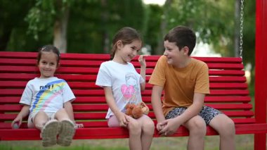 Neşeli çocuklar neşeli anların tadını çıkarırlar, doğada canlı bir salıncakta gülücükler ve hikayeler paylaşırlar..