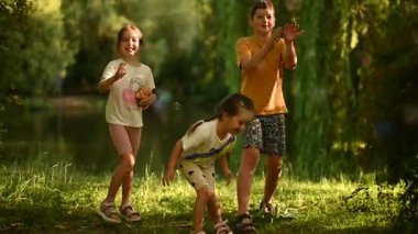 Kaygısız çocuklar güzel bir doğal park ortamında dışarıda sabun köpükleriyle oynuyorlar..