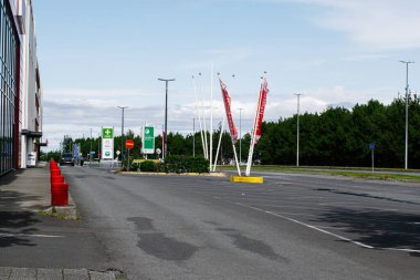 Reykjavik, İzlanda - 28 Haziran 2025: Reykjavik 'te modern bir bina, bayraklar ve yeşil ağaçların yanındaki boş şehir otoparkı.