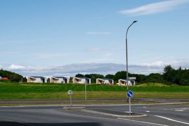 Reykjavik, İzlanda - 28 Haziran 2025: Reykjavik, İzlanda yakınlarında mavi gökyüzü olan yeşil tarlalı modern evler