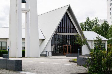 Reykjavik, İzlanda 'da bulutlu gökyüzü altında modern beyaz kilise ve çan kulesi.