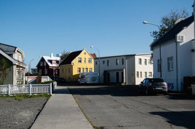 Akranes, İzlanda - 06 Temmuz 2025: Akranes, İzlanda 'da açık mavi gökyüzü altında güneşli bir caddede uzanan büyüleyici evler.