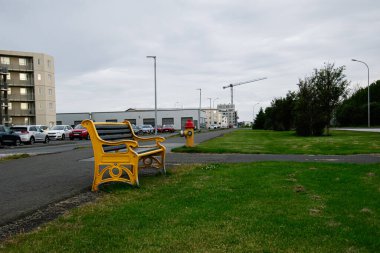 Akranes 'te park yolu manzarası, sarı bank ve kentsel arka plan.