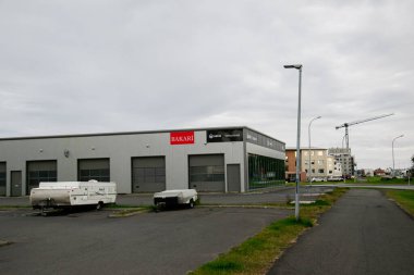 Akranes, İzlanda - 10 Temmuz 2025: Akranes, İzlanda 'da önünde karavan park edilmiş gri ticari bina.