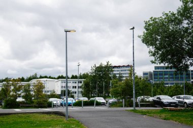 Reykjavik, İzlanda - 12 Temmuz 2025: Reykjavik, İzlanda 'da modern binalar, sokak lambaları ve park halindeki arabaların yer aldığı şehir manzarası