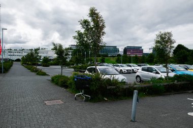 Reykjavik, İzlanda - 12 Temmuz 2025: Gri bir gökyüzü altında İzlanda 'nın Reykjavik kentinde çalılar ve ağaçlarla çevrili park yeri