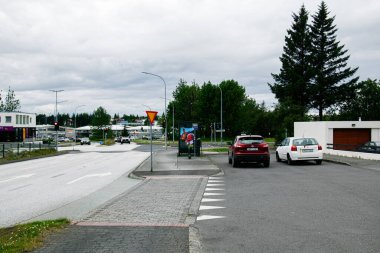 Reykjavik, İzlanda - 12 Temmuz 2025: Reykjavik, İzlanda 'da park halindeki arabaların ve yeşil ağaçların yer aldığı sakin bir şehir caddesi.