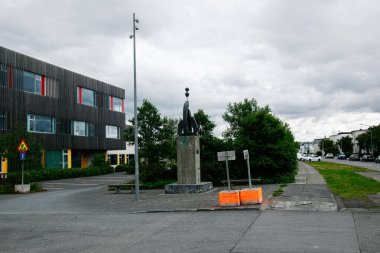 Reykjavik, İzlanda - 12 Temmuz 2025: Reykjavik sokak manzarası bir heykel, mimari Menntasklinn vi Sund, yeşillik ve kentsel altyapı.