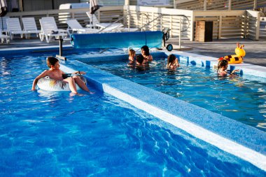 Bir grup çocuk temiz, parlak bir havuzda oynamayı ve su sıçratmayı seviyor..