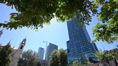 Varşova, Polonya - 02 Temmuz 2025: Büyüleyici modern gökdelenler ve Polonya 'nın Varşova kentinde açık bir gökyüzü altında karşıt tarihi kilise.