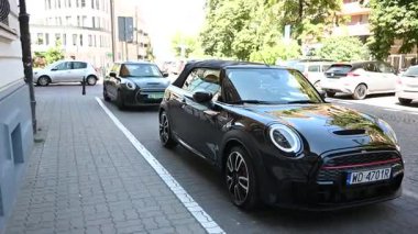 Varşova, Polonya - 02 Temmuz 2025: Siyah Mini Cooper üstü açık arabaları Polonya 'nın Varşova şehrinde canlı bir cadde boyunca park etti.