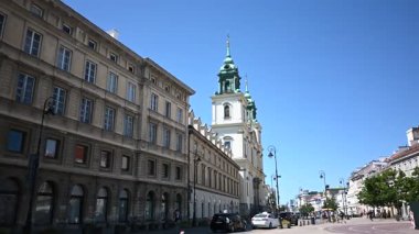 Varşova, Polonya - 02 Temmuz 2025 Varşova, Polonya 'da güneşli bir gün, büyük kilise ve büyüleyici tarihi şehir mimarisi sergileniyor. Kutsal Haç Kilisesi