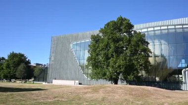 Varşova, Polonya - 02 Temmuz 2025: Polonya 'nın Varşova kentindeki POLIN Müzesinin belirgin mimarisini açık mavi bir gökyüzü altında göstermek.