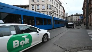 Krakow, Polonya - 08 Temmuz 2025: Modern bir mavi tramvay Polonya 'nın canlı kentsel manzarası boyunca hareket ederek günlük yaşamı gözler önüne seriyor.