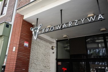 Varşova, Polonya - 02 Temmuz 2025: Varşova, Polonya 'da kendine özgü neon işareti olan bir vegan KROWARZYWA restoran girişi.